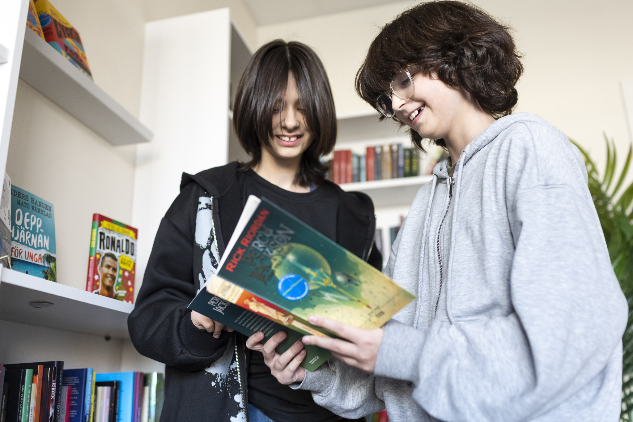 2 elever som tittar i en bok på skolbiblioteket
