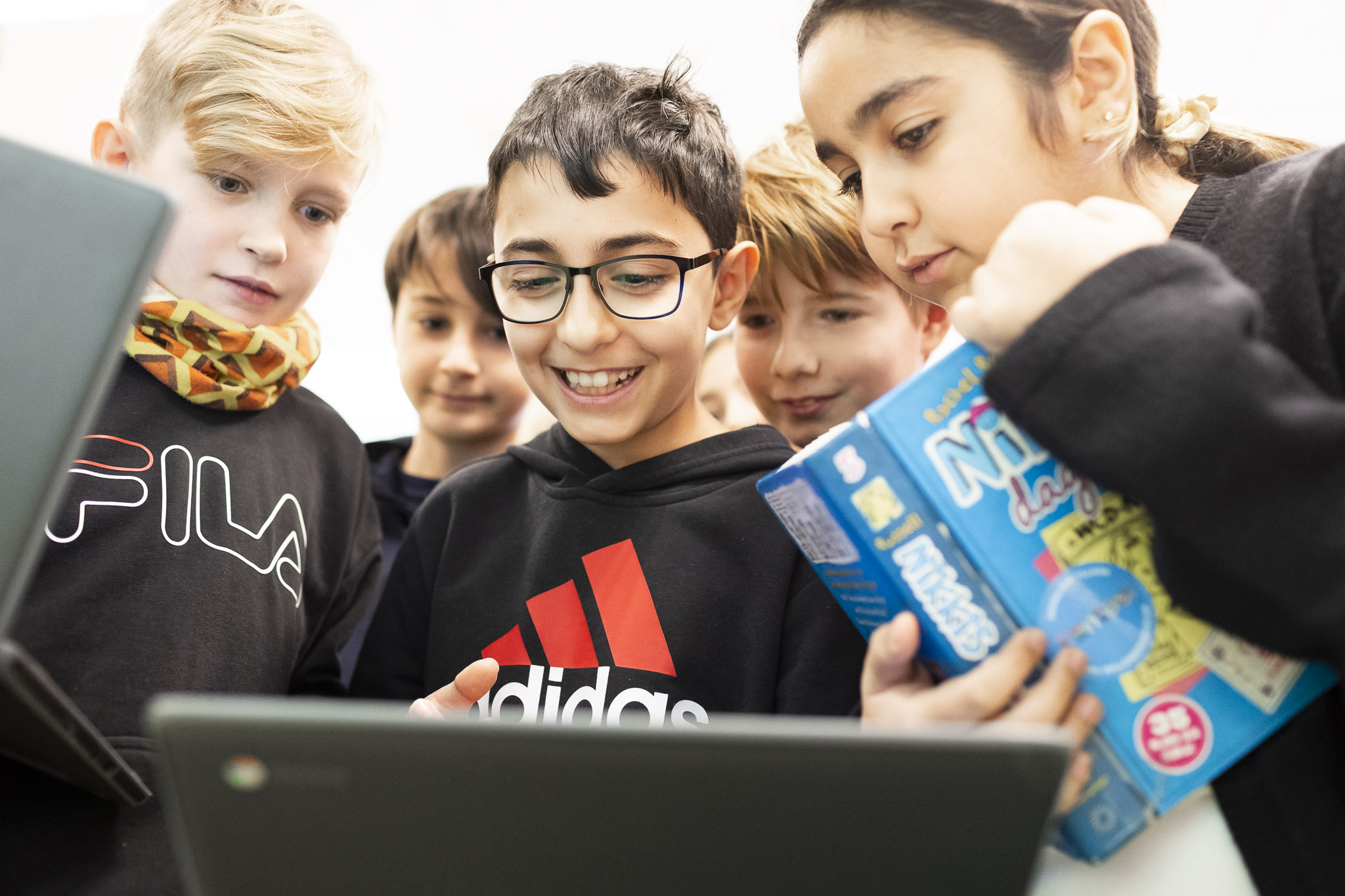 Elever som tittar ner i en dator och ser nyfikna ut.